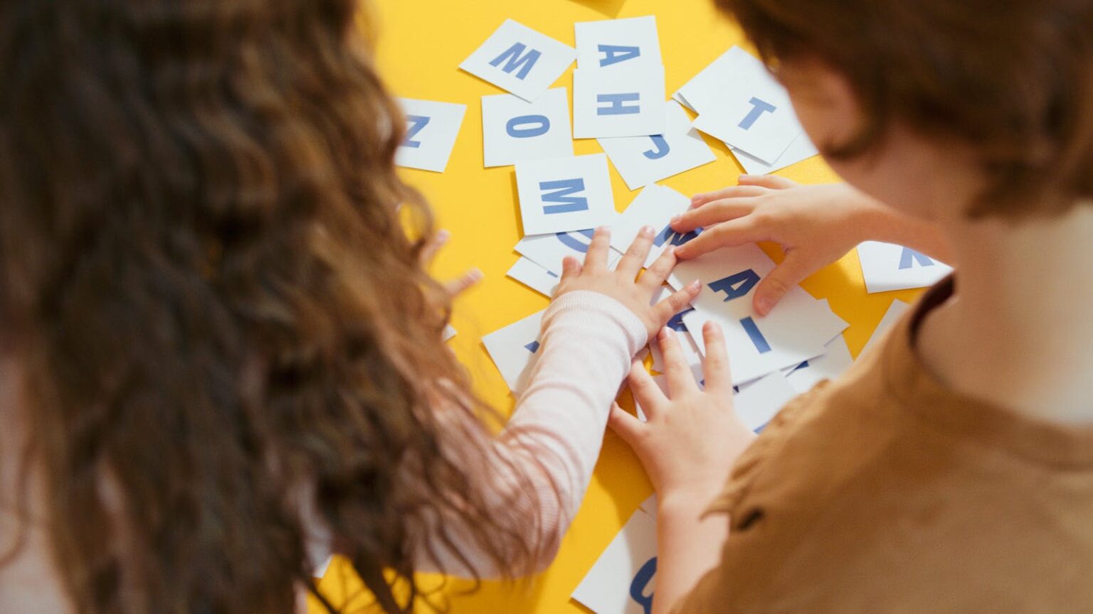 Two children playing with letter cards, enhancing their learning through a fun educational activity.